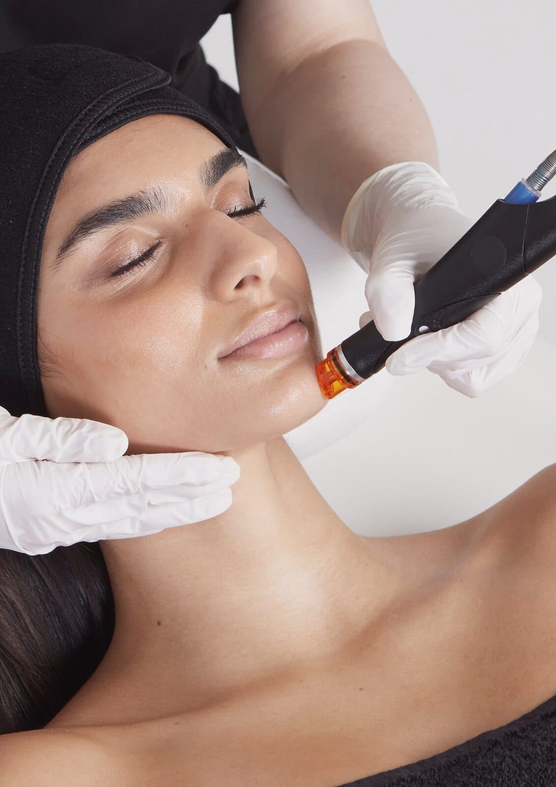 Handstück eines HydraFacial-Geräts mit orangefarbenem Aufsatz an der Kieferlinie